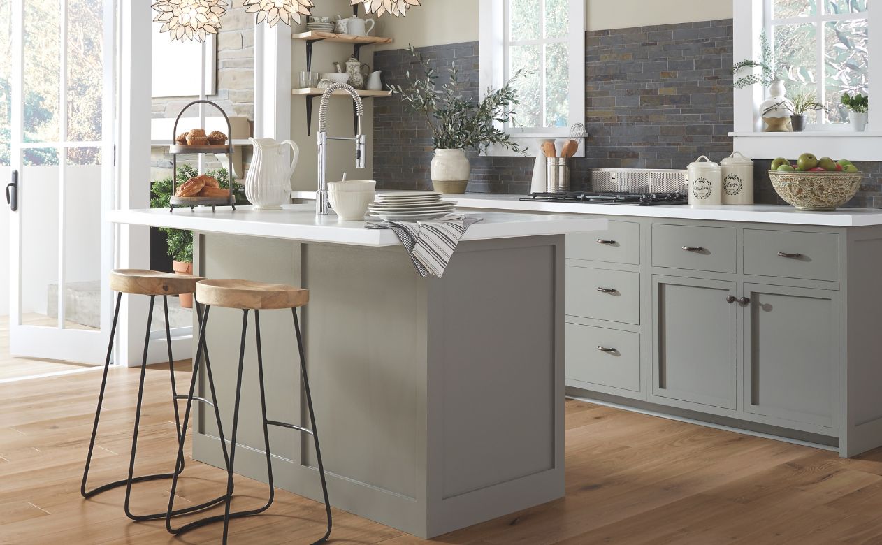 kitchen design with grey cabinets, wood look floors, dark tile backsplash, and stone countertops